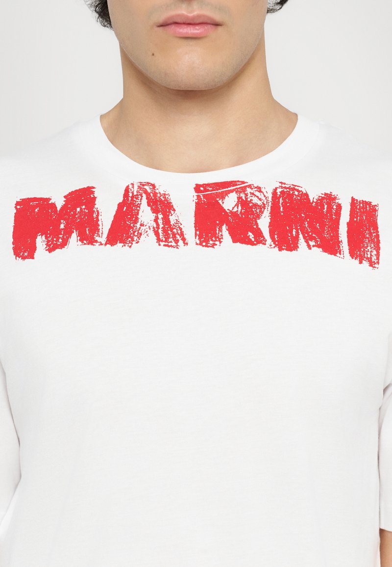 T-shirt en coton blanc avec un texte en rouge en coup de pinceau audacieux écrivant "MARNI" sur la poitrine ; manches courtes et col rond.