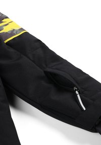 Manica di giacca nera con un motivo mimetico e dettagli gialli, una tasca con zip e una texture liscia.