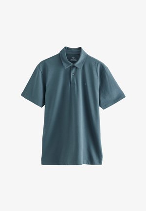 Teal värvi puuvillane polo särk, millel on krae, kahe nupuga nööpauk, lühikesed varrukad ja diskreetne logo rinnal. Sujuv tekstuur.