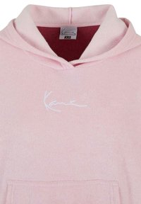 Roze hoodie met een textuurstof, voorzien van een voorzak en een witte geborduurde logo op de borst. Label toont maat XS.