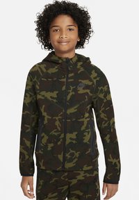 Felpa con zip mimetica in verde scuro e marrone, realizzata in tessuto morbido. Presenta un cappuccio, tasche con zip e un logo sul lato sinistro del petto.