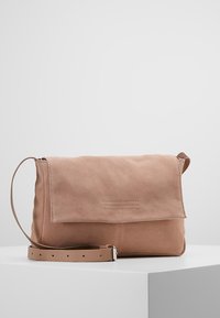 Světle růžová semišová crossbody taška s překlápěcí klopou, prošívanými detaily a nastavitelným popruhem pro všestranné možnosti nošení.