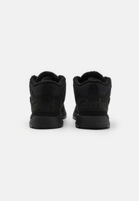 Botas Timberland negras con un material exterior texturizado, forro suave, tobillo acolchado y suela de goma. Presentan un sutil logotipo en el talón.