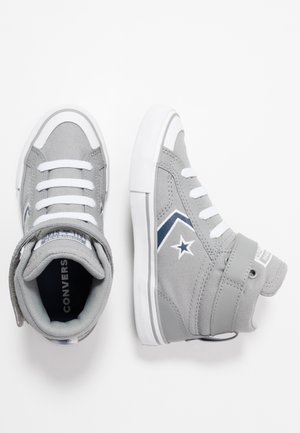 Scarpe da ginnastica Converse alte grigie con lacci bianchi, logo a stella blu navy e una striscia in Velcro su sfondo bianco.