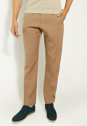 Beige katoenen broeken met een rechte snit, frontzakken en een gladde textuur. Gecombineerd met donkerblauwe schoenen en een lichte trui.