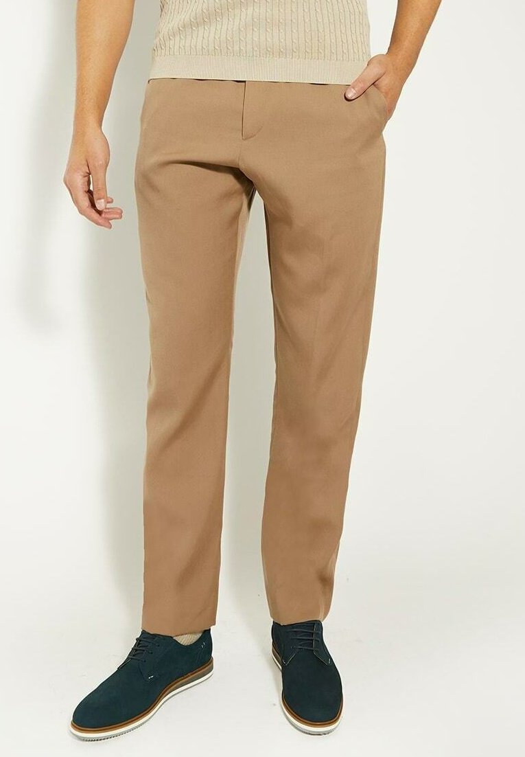 Beige katoenen broeken met een rechte snit, frontzakken en een gladde textuur. Gecombineerd met donkerblauwe schoenen en een lichte trui.