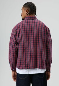 Rood- en blauw geruit overhemd met lange mouwen, knoopmanchetten en een afgeronde zoom. Gemaakt van katoen met een ontspannen pasvorm en een klassiek kraagontwerp.