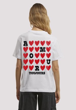 T-shirt en coton blanc avec un motif de cœur rouge et un texte noir audacieux épelant "AMOUR TOUJOURS" au dos.