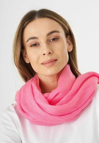 Écharpe rose vif en tissu léger, enroulée lâchement autour du cou, avec une texture douce et un tombé fluide.