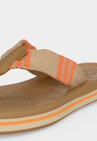 Sandale en tissu beige et orange rayé avec une semelle marron texturée présentant des motifs floraux et une bande intermédiaire beige et orange en couches.