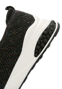 Black knit sneaker with multicolor specks, white sole, textured black accent on heel, and pull tab at the back. Lightweight design.