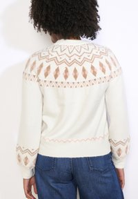 Balts džemperis ar ģeometrisku rozā un metalizētu akcentu džinsu. Ar puffie piedurknēm un ribota apakšmala. Parādīta aizmugurējā skats.