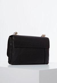 Sort læderhåndtaske med rektangulær form, der har en klaplukning og metalhardware. Overfladen har en tekstureret finish.