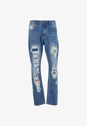 Sinine denim teksad, millel on mitmed kulunud augud, mis paljastavad allolevad värvilised kangapatchid, ja klassikaline viie taskuga disain.