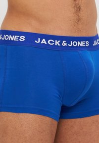 Blaue Baumwollboxershorts mit einem kontrastierenden blauen Gummibund, auf dem "JACK & JONES" in Weiß gedruckt ist. Maschinennahtverarbeitung.