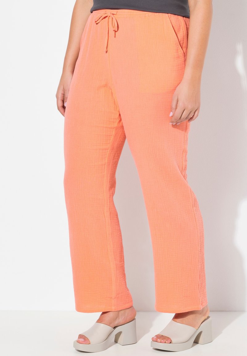Lichte, textuurrijke broek in koraal met een elastische tailleband en trekkoord. Gecombineerd met beige blockhakken muiltjes.