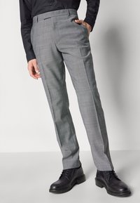 Grau karierten Hosen mit geradem Bein, flachem Bund und Seitentaschen, kombiniert mit schwarzen Schnürschuhen. Maßgeschneidertes Design und elegant fallend.