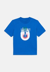 Camiseta de algodón azul con el texto "ITALIA", acentos en verde y rojo, y un gráfico circular con un logotipo y un patrón ondulado. Mangas cortas y cuello redondo.