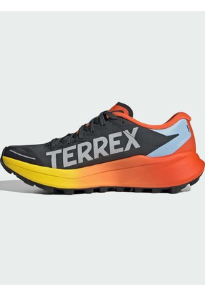 Czarno-pomarańczowy but do biegania po szlakach z żółtą, gradientową podeszwą, logo "TERREX" na boku oraz sznurowaniem z przodu, zaprojektowany do użytku na zewnątrz.