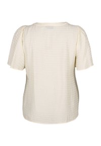 Blusa corta a maniche corte di colore crema con un motivo testurizzato a griglia. Vestibilità rilassata, scollatura rotonda e tessuto morbido. Vista posteriore mostrata.