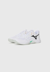 White athletic shoes with a textured upper, rubber sole, black accents, and orange eyelets. Features a green logo on the sole.