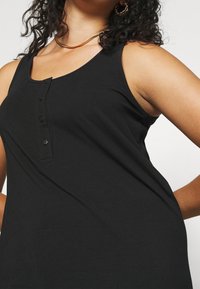 Schwarzes Tanktop aus weichem Stoff, mit rundem Halsausschnitt, ärmellosem Design und Knopfdetails auf der Vorderseite.