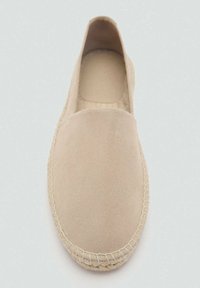 Beige suede slip-on shoe with a round toe, minimal stitching around the edge, and a smooth texture. Flat, simple design.