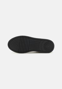 Semelle de chaussure en caoutchouc noir avec un motif strié, dotée de points de traction circulaires et de bords incurvés lisses. Design durable et flexible.
