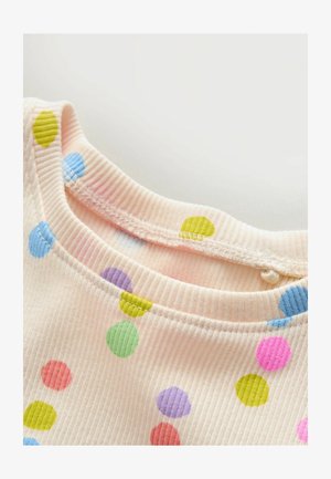 Soft ribbed fabric neckline of a light pink garment with multicolored large polka dots in green, blue, purple, pink, and red.