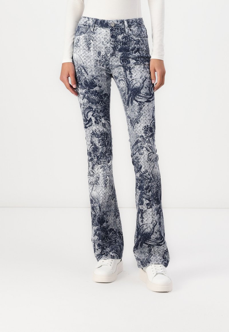 Sbukser med en blå blomstermønster på en lys bakgrunn. Laget av denim, med frontlommer og knappelukking.