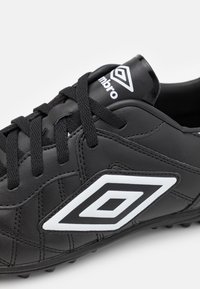 Black sports shoe made of synthetic leather with textured surface, featuring a white logo and accent, traditional lacing, and molded outsole.