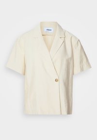 Blazer crème à manches courtes, fermeture par un bouton et col à revers cranté, présenté sur un fond uni.