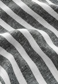 Tissu rayé noir et blanc avec un tissage texturé, présentant des rayures larges et étroites alternées dans une finition lisse et douce.