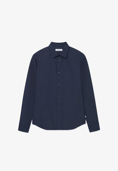 Mørkeblå langermet skjorte med vertikale striper, knappestolpekrage, enkelt brystlomme, og buet nederkant. Laget av mykt stoff.