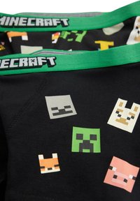 Musta lasten alushousut, joissa on värikkäitä pikselöityjä hahmoja Minecraftista. Vyötäröllä vihreä elastinen vyö, jossa lukee "MINECRAFT."