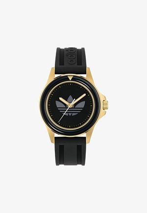 Crni gumeni remen sat s kućištem u zlatnoj boji, crnim brojčanikom koji sadrži uzdignuti crni logo i srebrne kazaljke za sate i minute, zlatni akcenti.