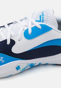Chaussure de sport présentant une combinaison de matériaux blancs, bleu marine et bleu clair. Tissu texturé et cuir lisse avec des accents bleus distinctifs.