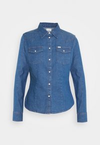 Mörkblå denimskjorta med långa ärmar, spetsig krage och två bröstfickor. Har vita tryckknappar och en figurnära design.