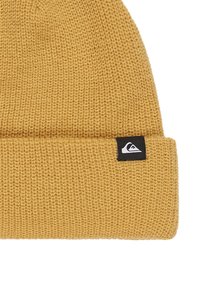 Mosterdgele gebreide beanie met een opgerolde rand en een klein zwart logo-opdruk aan de zijkant. Gestructureerde stof met een strakke pasvorm.