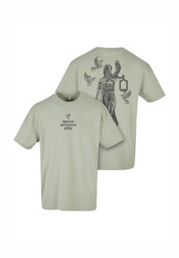 Lysegrøn bomulds T-shirt med et grafisk print af en figur, der holder vægte og duer, med teksten "uskyldig indtil det modsatte er bevist."