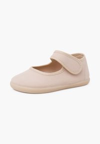 Chaussure Mary Jane en tissu beige clair avec un bout arrondi et une bride en Velcro réglable sur fond blanc.