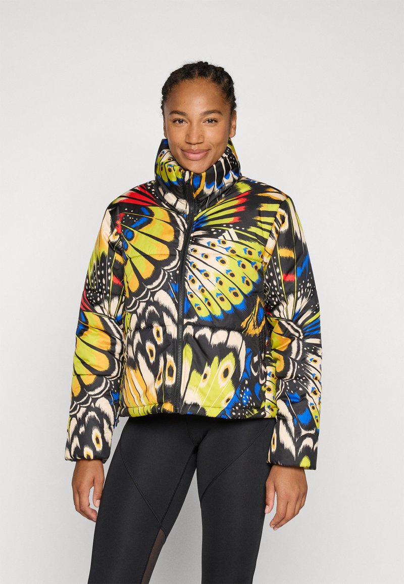 Casaco acolchoado com um padrão de borboleta colorido, gola alta, fecho com zip e um acabamento brilhante. Usado com leggings pretas justas.
