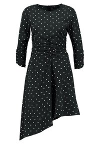 Černé šaty s bílými puntíky, dlouhé rukávy, řasený přední díl, asymetrický lem, hladká látka. Design zahrnuje kulatý výstřih a zip na zadní straně.