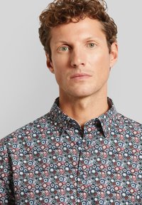 Gemustertes Hemd mit Knöpfen, das eine Mischung aus kreisförmigen Motiven in Rot, Weiß und Marineblau auf einem dunklen Hintergrund zeigt; aus Baumwolle, mit umgeschlagenem Kragen.