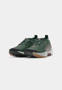 Green athletic shoes with a textured upper, black and light gray soles, reflective accents, and a pull tab at the heel for easy wear.