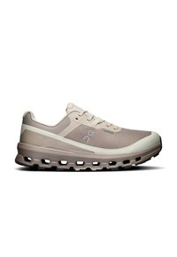 Baskets de course beige avec une tige en maille texturée, semelle rembourrée et découpes distinctives. Présente un logo sur le côté et un design à lacets.