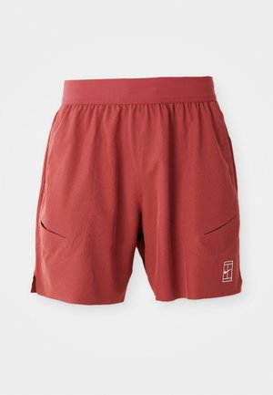 Red athletic shorts with an elastic waistband, two side pockets, and a small logo on the lower right. Smooth texture, mid-thigh length.