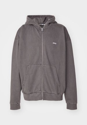 Kullgrå zip-up hettegenser laget av bomull. Har hette, frontlommer og en brodert logo på brystet. Ribbestrikkede mansjetter og nederkant.