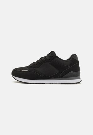Svart atletiska sneakers med en texturerad ovandel, vadderad krage och en vit mellansula med en svart gummisula.