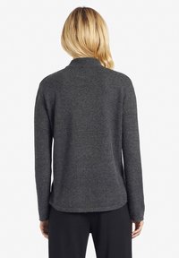 Ciemnoszary sweter z dzianiny o wysokim dekolcie, długich rękawach i textured powierzchni. Posiada luźny krój i boczne rozcięcia na dole.